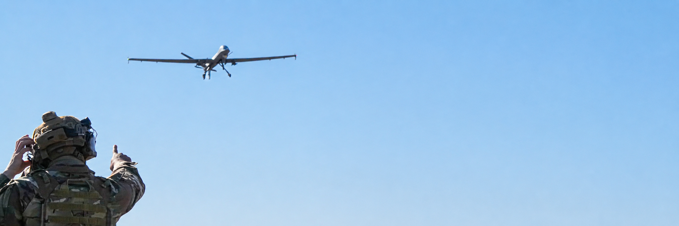 A U.S. Air Force Airman gives a thumbs-up while watching an MQ-9 Reaper unmanned aircraft in flight.